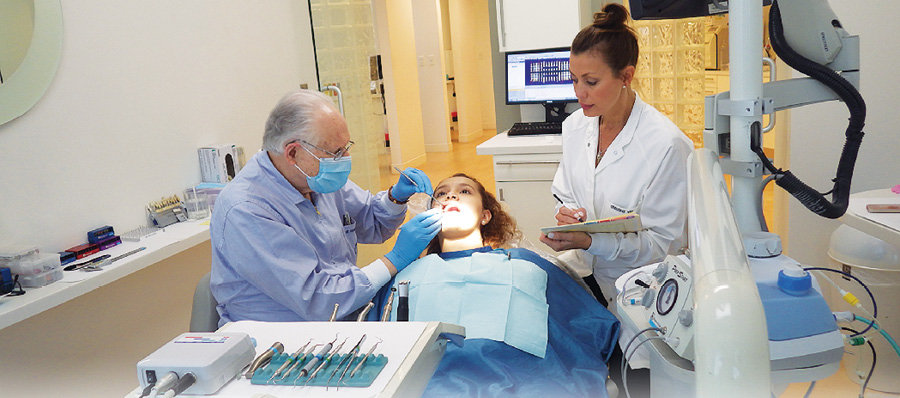 Figure 1 : In the first scenario, the patient makes an appointment for a consultation with the dentist and dental assistant. In the photo, Dr. Goldstein examines the new patient with Christina Via, the dental assistant, who writes down his notes.